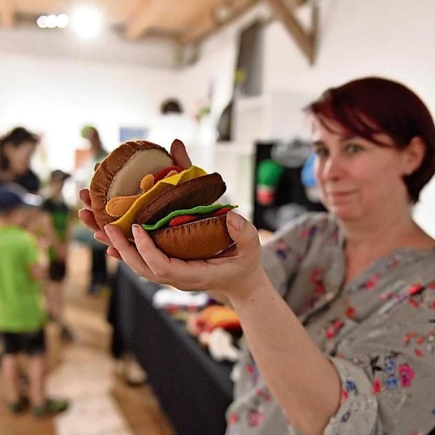 Über Mimimade Hier sieht man mich wie ich einen realistisch aussehenden Hamburger in der Hand vorzeige.