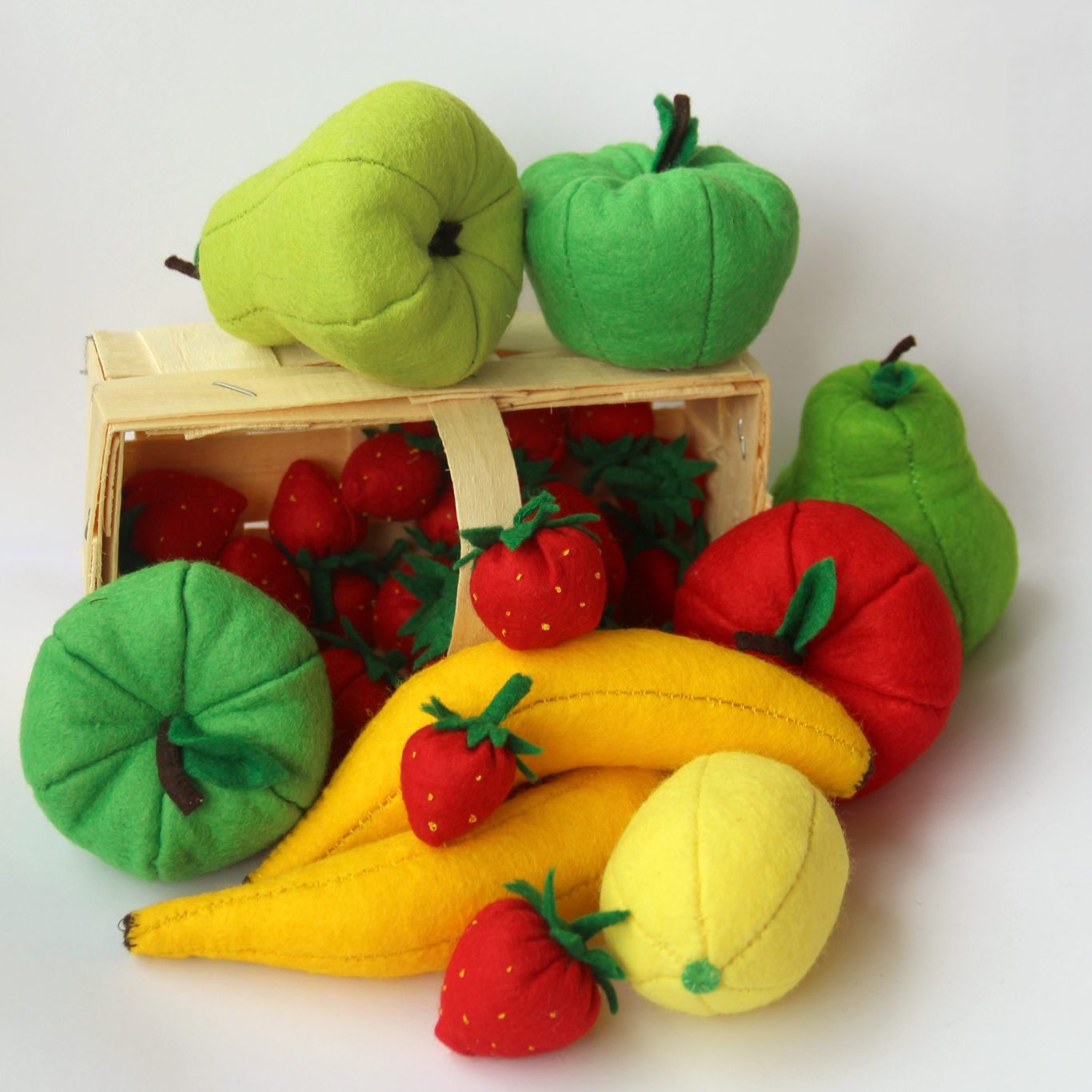 Onlline Shop Bunte, weiche Obstspielzeuge in einer Kiste, darunter Äpfel, Bananen und Erdbeeren.